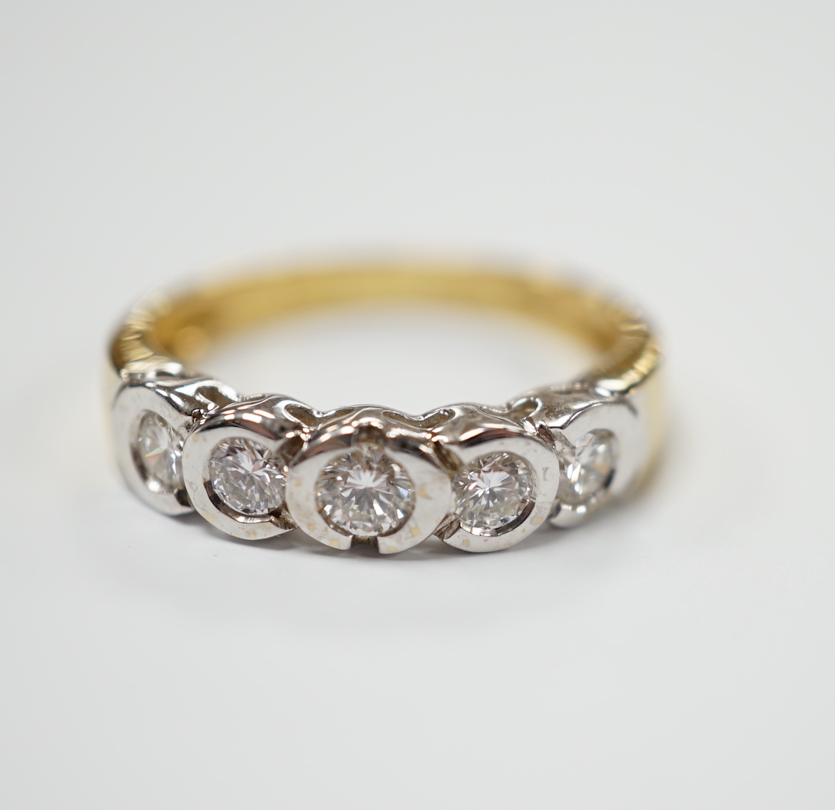 A modern 18ct gold and collet set five stone diamond half hoop ring, size O, gross weight 3.5 grams.